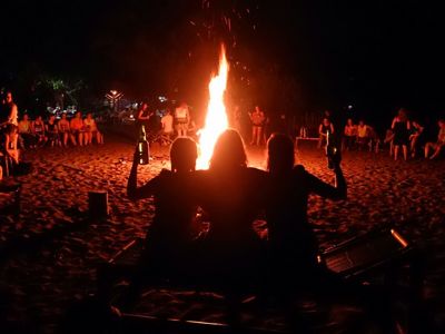 Gezellig kampvuur op het strand tijdens de Route Bali & Lombok, met reizigers die ’s avonds samenkomen.