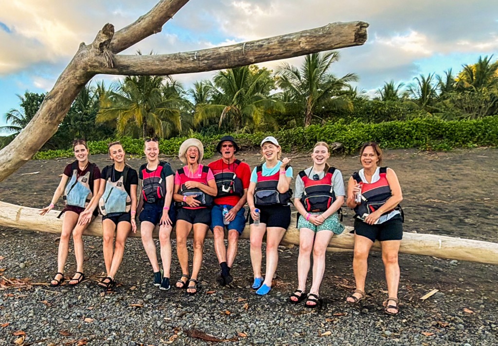 Groep reizigers op zwart zandstrand met palmbomen tijdens groepsrondreis Costa Rica Hoogtepunten.