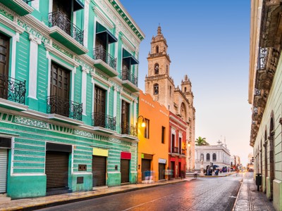 Kleurrijke gevels in historisch centrum van Mérida, Mexico, met kathedraal op de achtergrond.
