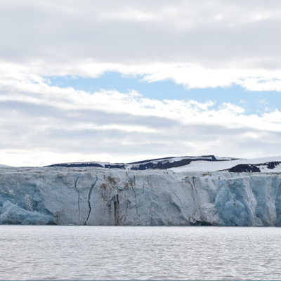 Kajakkers bij een imposante gletsjerwand in Spitsbergen, tijdens groepsrondreis naar Groenland en IJsland.