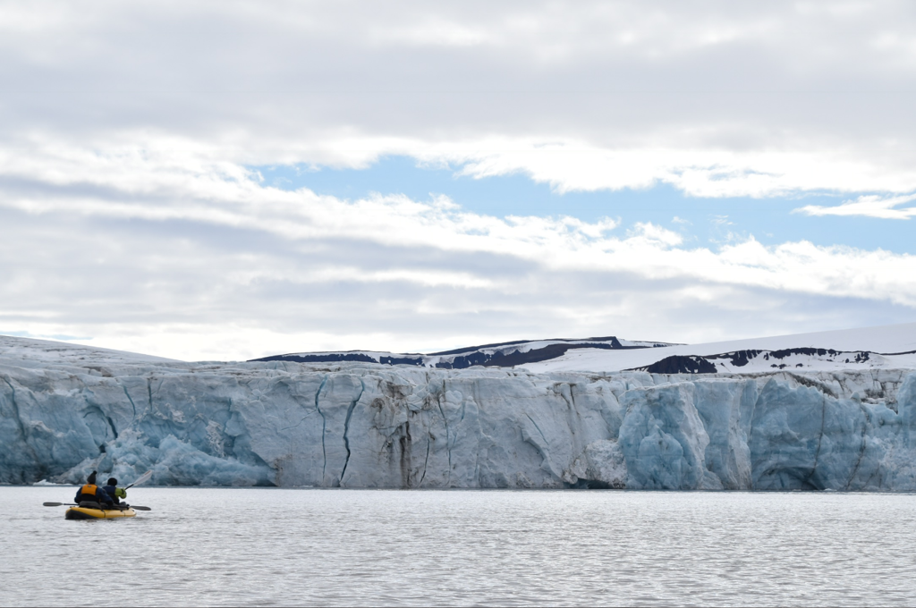 Kajakkers bij een imposante gletsjerwand in Spitsbergen, tijdens groepsrondreis naar Groenland en IJsland.