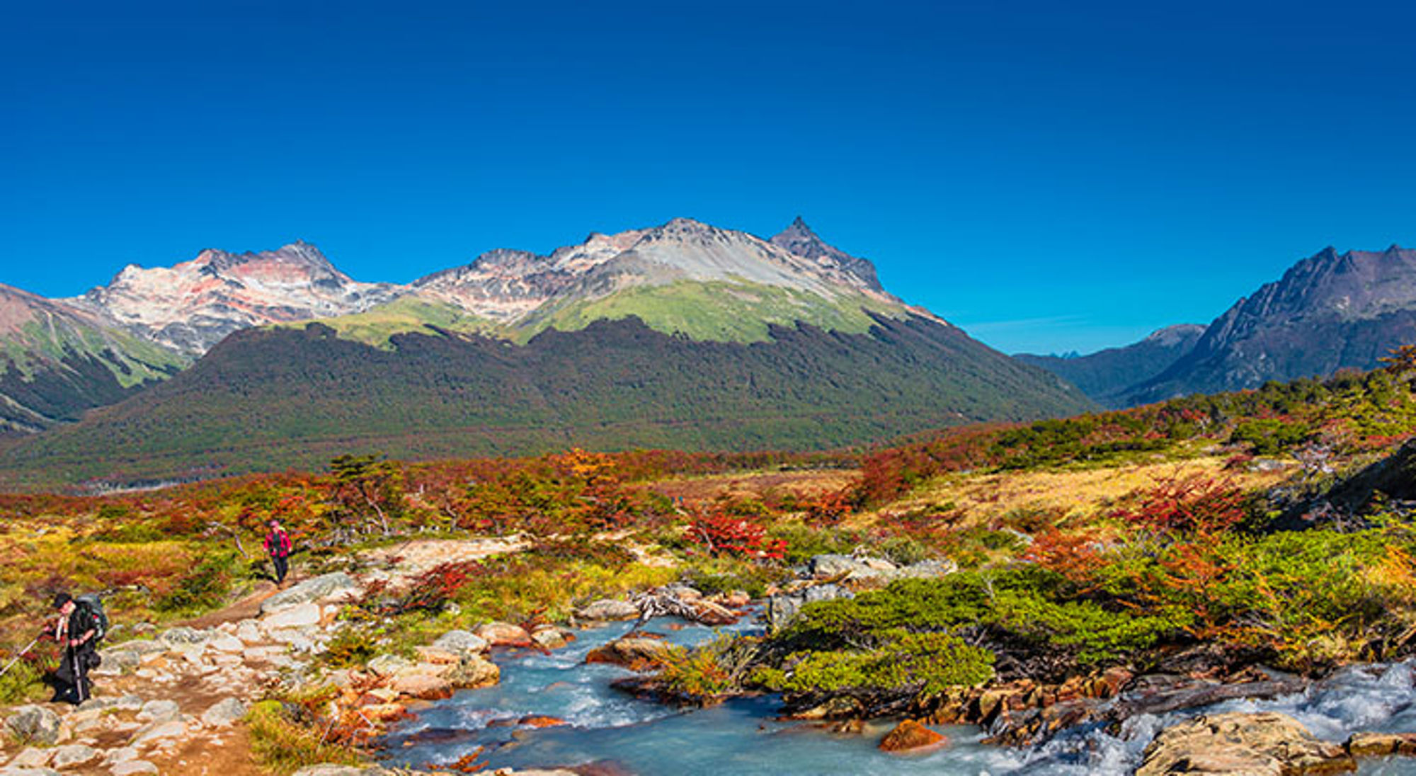 Wandelpad langs een rivier met bergen op de achtergrond in Patagonië.