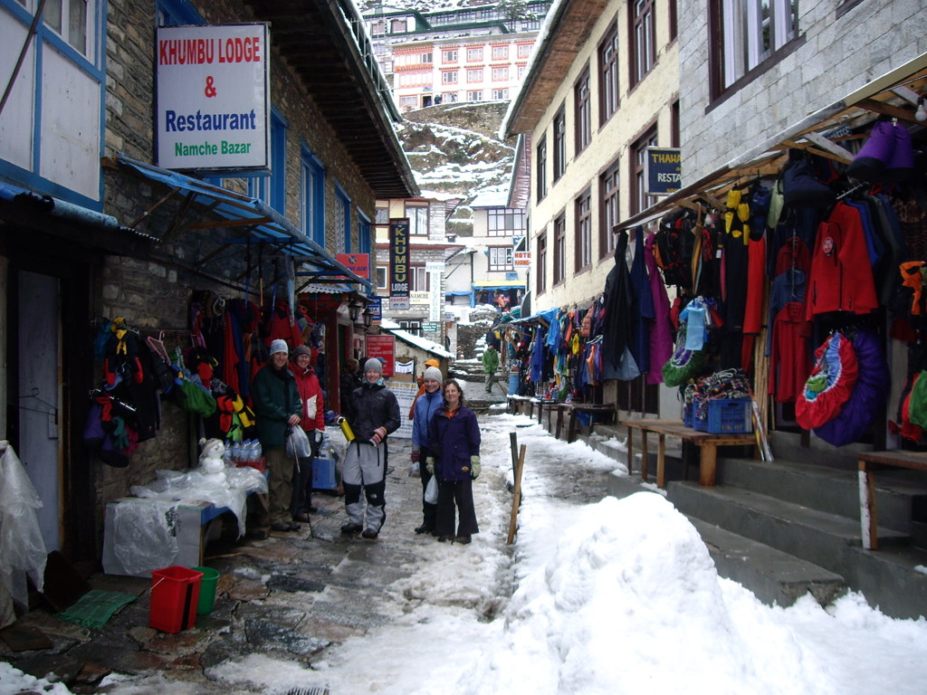 Groepsrondreis Nepal Everest: trekkers in de besneeuwde hoofdstraat van Namche Bazaar met lodges en winkels.