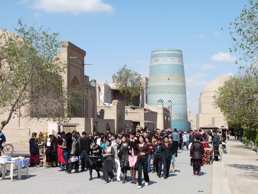 Drukke straat in Khiva met de turquoise Kalta Minor-minaret tijdens een groepsrondreis over de Zijderoute.