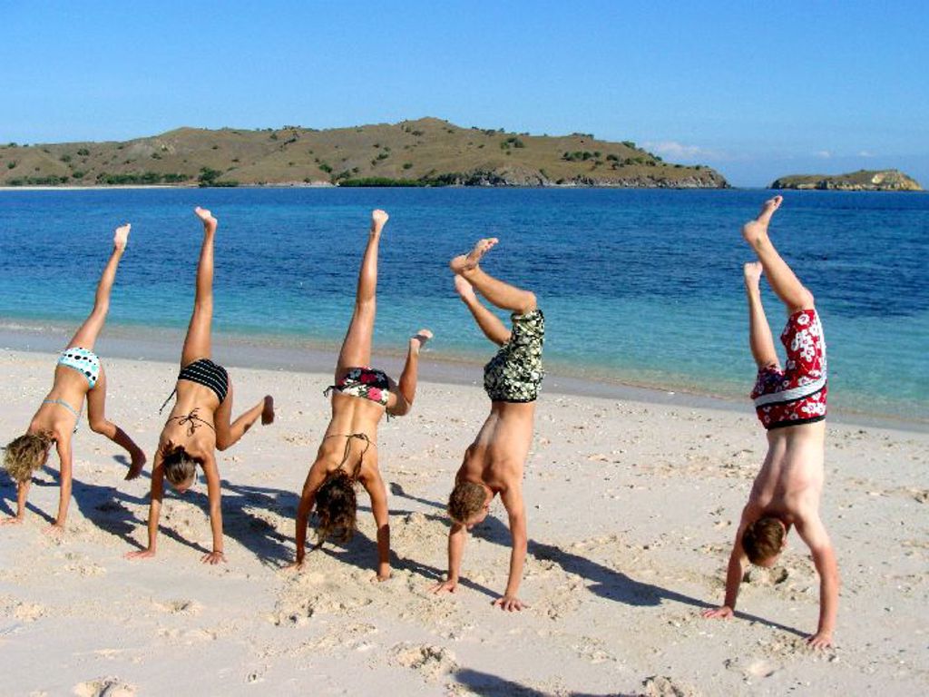 Kinderen doen handstanden op het strand bij de Kleine Sunda Eilanden in Indonesië.