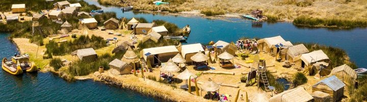 Uitzicht op het Titicacameer in Peru met rietvelden en bergen op de achtergrond.