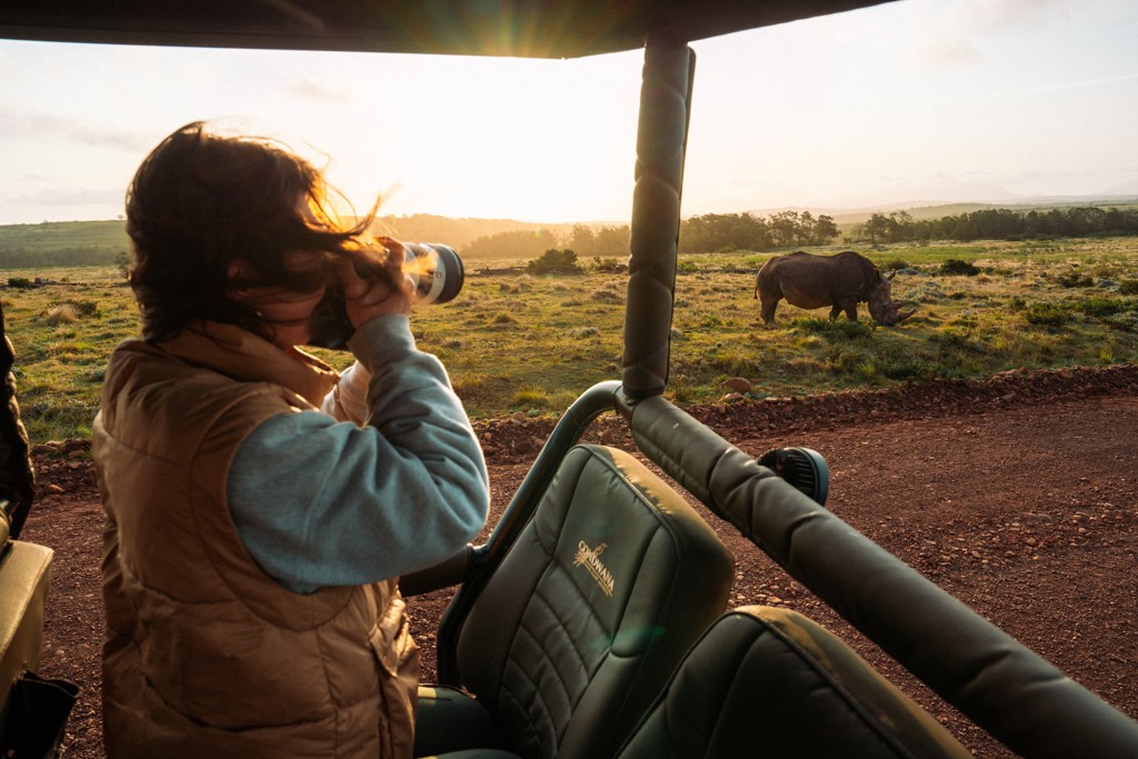 Reiziger spot een neushoorn tijdens safari in Zuid-Afrika bij zonsondergang.