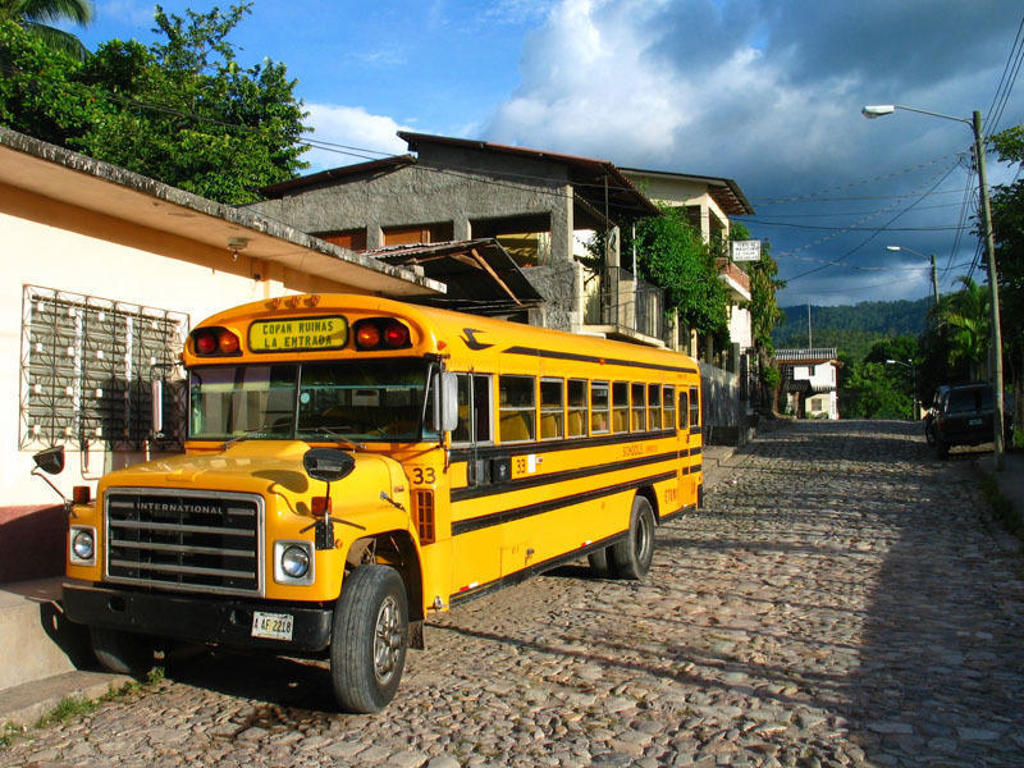 Gele schoolbus op een geplaveide straat in Midden-Amerika tijdens groepsrondreis Mexico, Guatemala en Honduras.