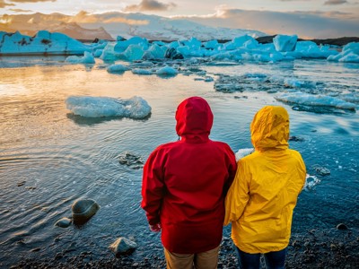 Twee reizigers kijken uit over de ijsbergen in Jökulsárlón gletsjerlagune tijdens zonsondergang in IJsland.