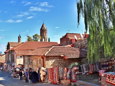 Straatmarkt met kleurrijke tapijten en kerk in Sighnaghi, Georgië.