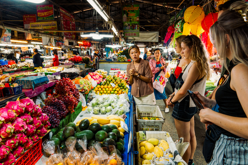 22-35ers groepsreis Thailand: reizigers op een lokale markt met kleurrijk fruit en groente.