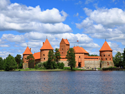 Kasteel Trakai in Litouwen aan het Galvė-meer, met rode torens onder een blauwe lucht.