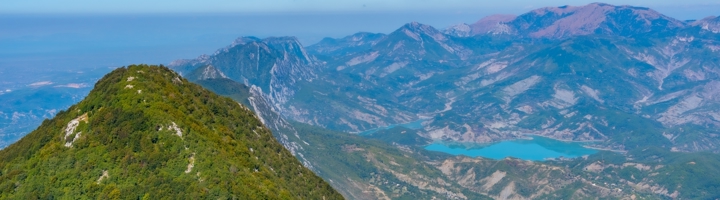 Uitzicht vanaf Mount Dajti over bergtoppen en een turquoise meer in Albanië.