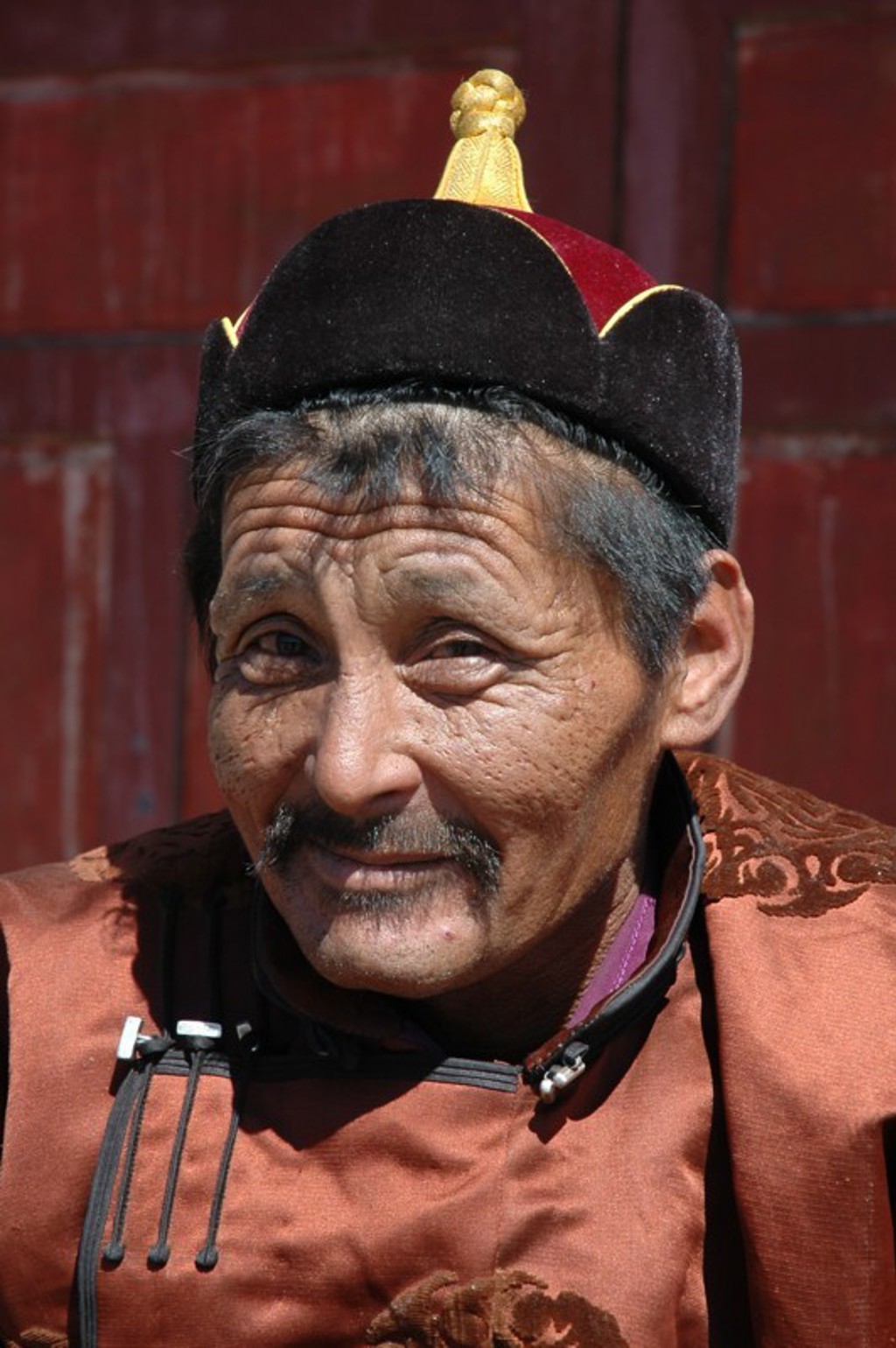 Portret van een Mongoolse man in traditionele kleding tijdens een groepsrondreis door Mongolië.