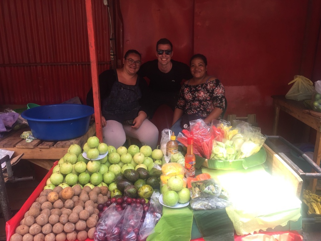 Reizigers bij een fruitkraam op de markt tijdens een 22-35ers groepsrondreis door Guatemala, Honduras en El Salvador.