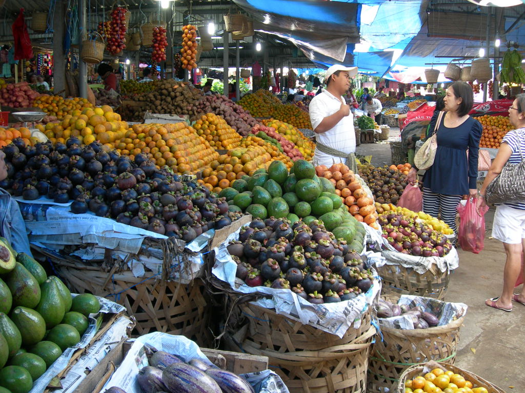 Drukke markt op Sumatra met kramen vol tropisch fruit en groente.
