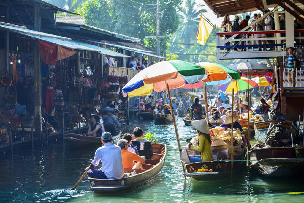 Drijvende markt in Thailand met boten vol fruit en kleurrijke parasols tijdens familiereis Thailand Hoogtepunten.