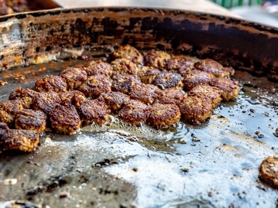 Streetfood in Noord-India: gekruide snackballetjes bakken in olie op een grote bakplaat.