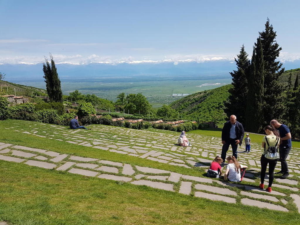 Uitzicht over groene heuvels en de besneeuwde Kaukasus tijdens een 22-35ers reis in Georgië.