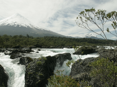Sneeuwbedekte vulkaan bij stromende rivier en watervallen in Patagonië.
