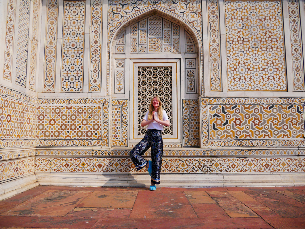 Reiziger doet yogapose voor rijk versierde gevel van het Taj Mahal-complex tijdens 22-35ers reis India.