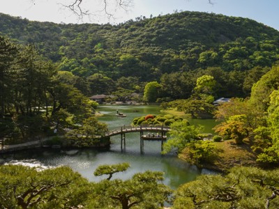 Japanse tuin met vijver, brug en groene heuvels langs de Route Japan.