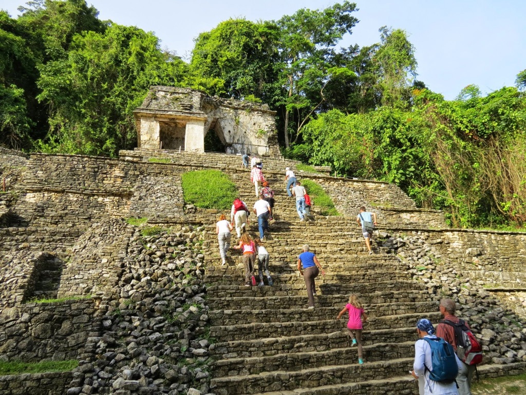 Gezin klimt de stenen trappen van een Maya-piramide in de jungle van Mexico op.