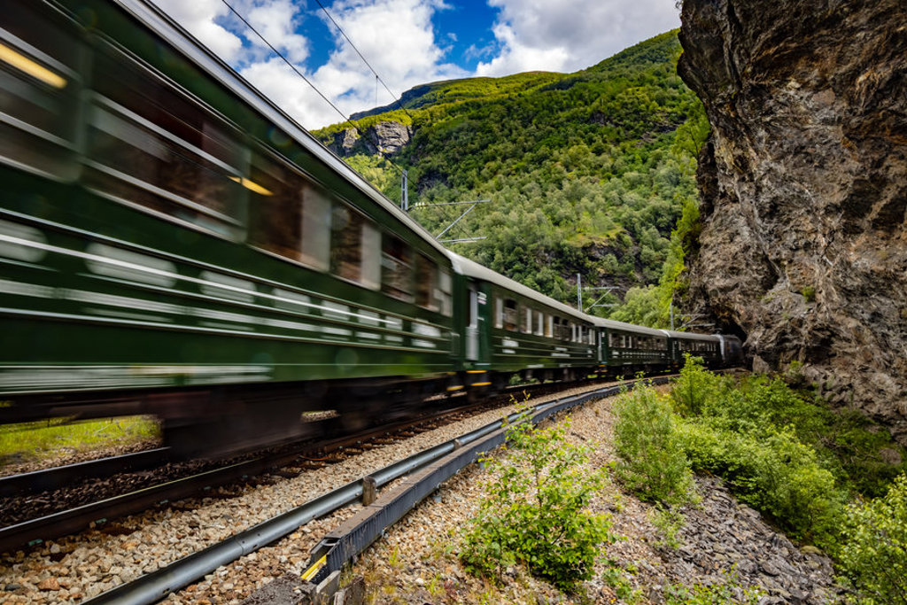 Groene trein rijdt door een bergachtig landschap in Scandinavië tijdens een groepsrondreis.