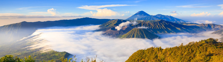 Panorama van de Bromo-vulkaan bij zonsopkomst op Java, Indonesië, met zee van wolken en bergketens.