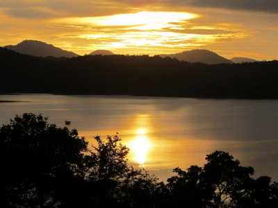 Zonsondergang boven een meer met silhouetten van heuvels en bomen in Sri Lanka.