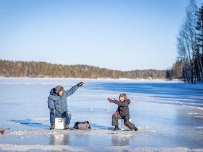 Vader en kind ijsvissen op een bevroren meer in Lapland, Route Lapland.