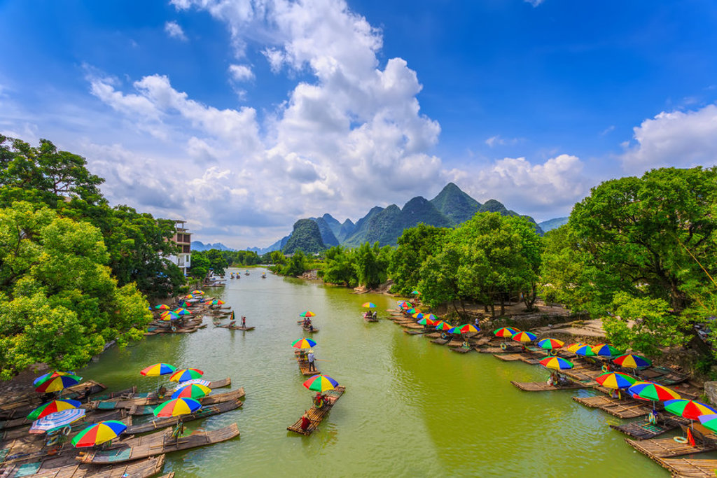 Bamboevlotten met kleurrijke parasols op de Li-rivier bij Guilin, met karstbergen op de achtergrond in China.