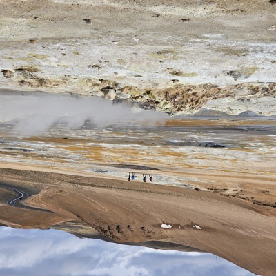 Wandelaars bij dampende geothermische bronnen in het vulkanische landschap van IJsland tijdens een groepsrondreis.