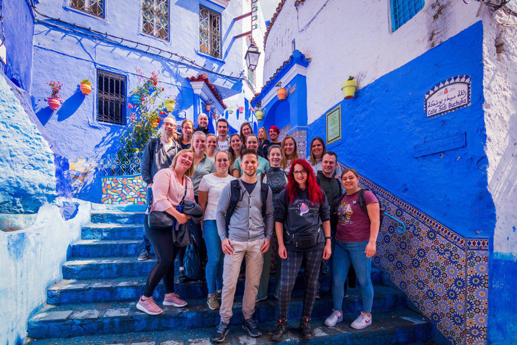 Groepsfoto van 22-35ers reis Marokko in de blauwgeschilderde straatjes van Chefchaouen.