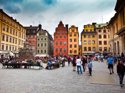 Drukke plein in Stockholm met kleurrijke historische gevels en fontein tijdens de Route Scandinavië, dag 11.