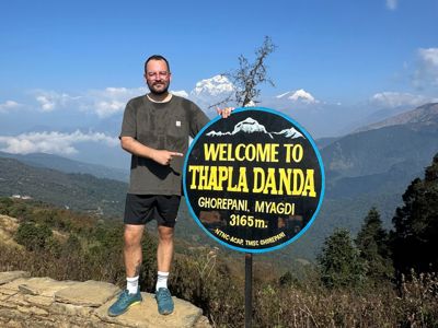 Wandelaar bij het bord ‘Welcome to Thapla Danda’ (3165 m) met uitzicht op de Himalaya tijdens de Route Nepal.