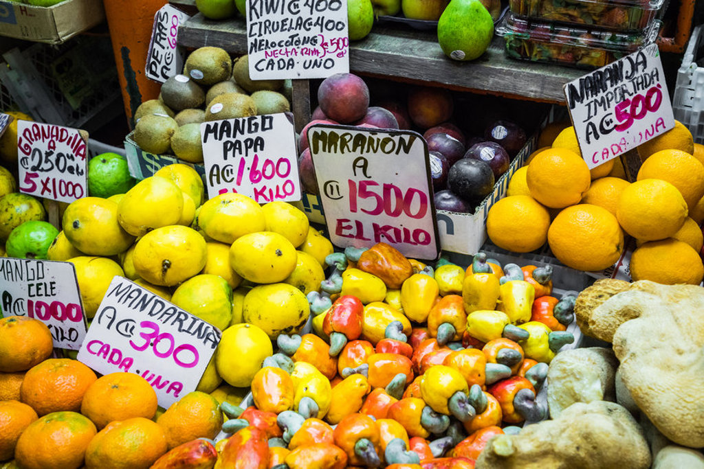 Kleurrijke fruitkraam op een markt in Costa Rica met citrus, mango’s en cashewnoten met prijskaartjes.