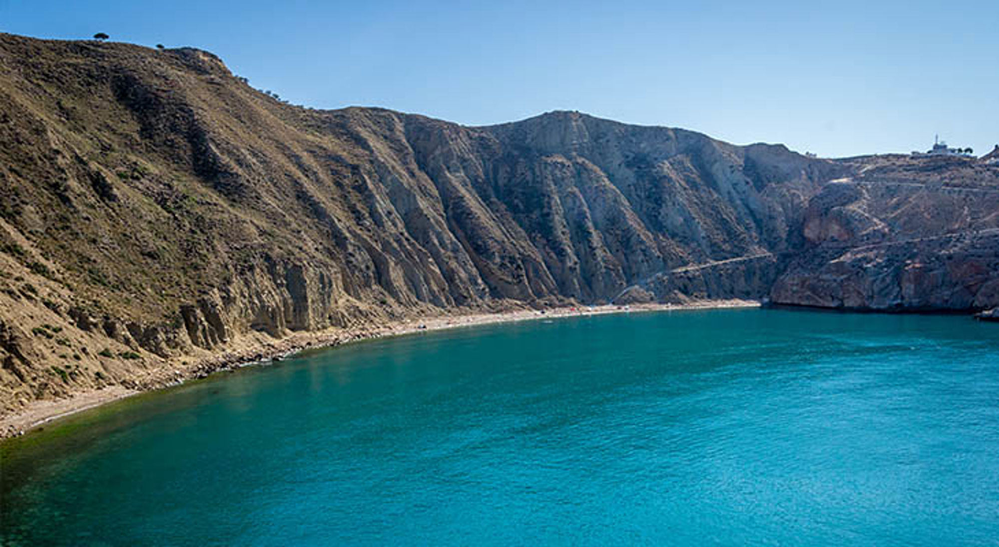Baai met turquoise water en steile rotskliffen aan de kust van Marokko.