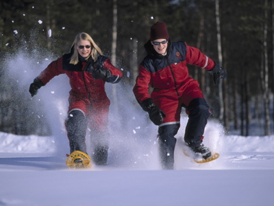 Sneeuwschoenwandeling in Lapland, Finland, met twee reizigers die door diepe sneeuw rennen.