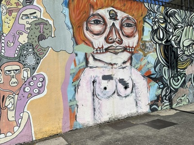 Streetartmuur in San José, Costa Rica, met kleurrijke graffiti van gezichten en abstracte vormen.