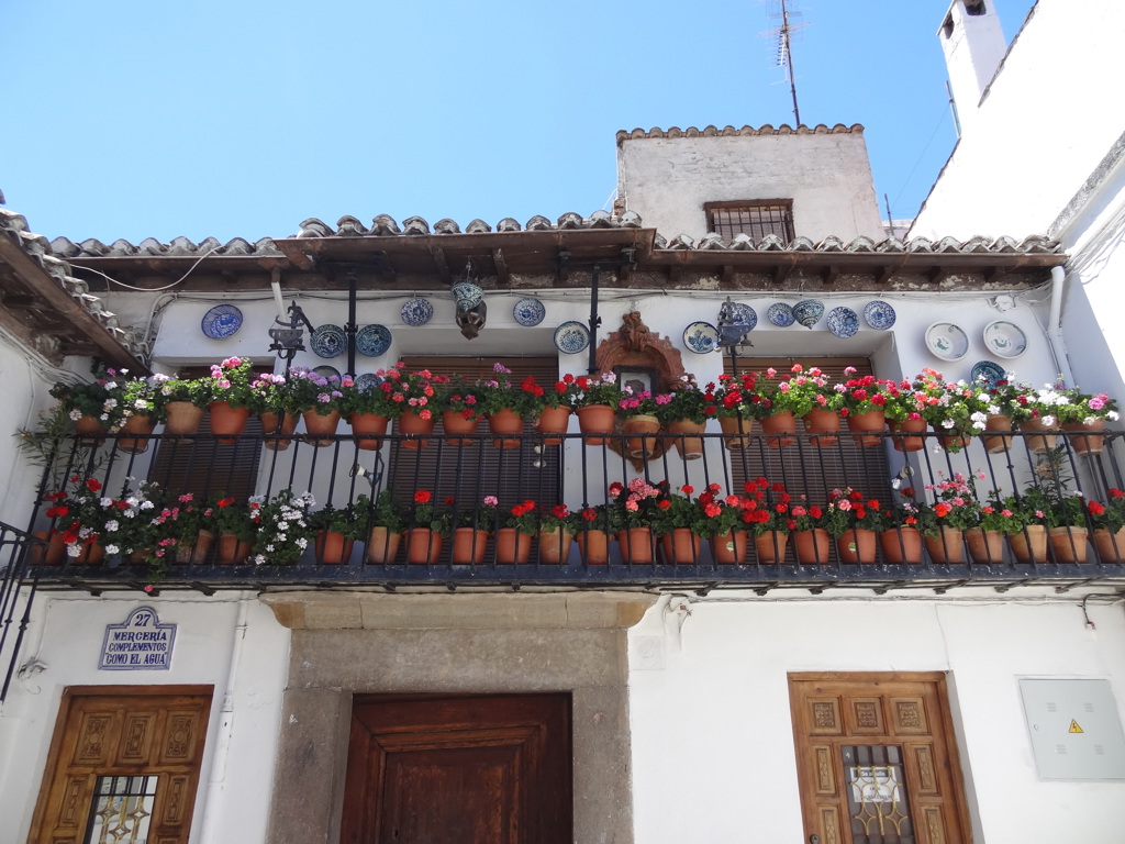Wit Andalusisch huis met balkon vol bloempotten en keramieken borden, tijdens groepsrondreis Andalusië.