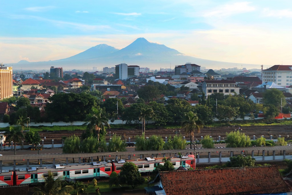 Stadsgezicht op Java met trein en de vulkaan Merapi op de achtergrond tijdens groepsrondreis Java & Bali.