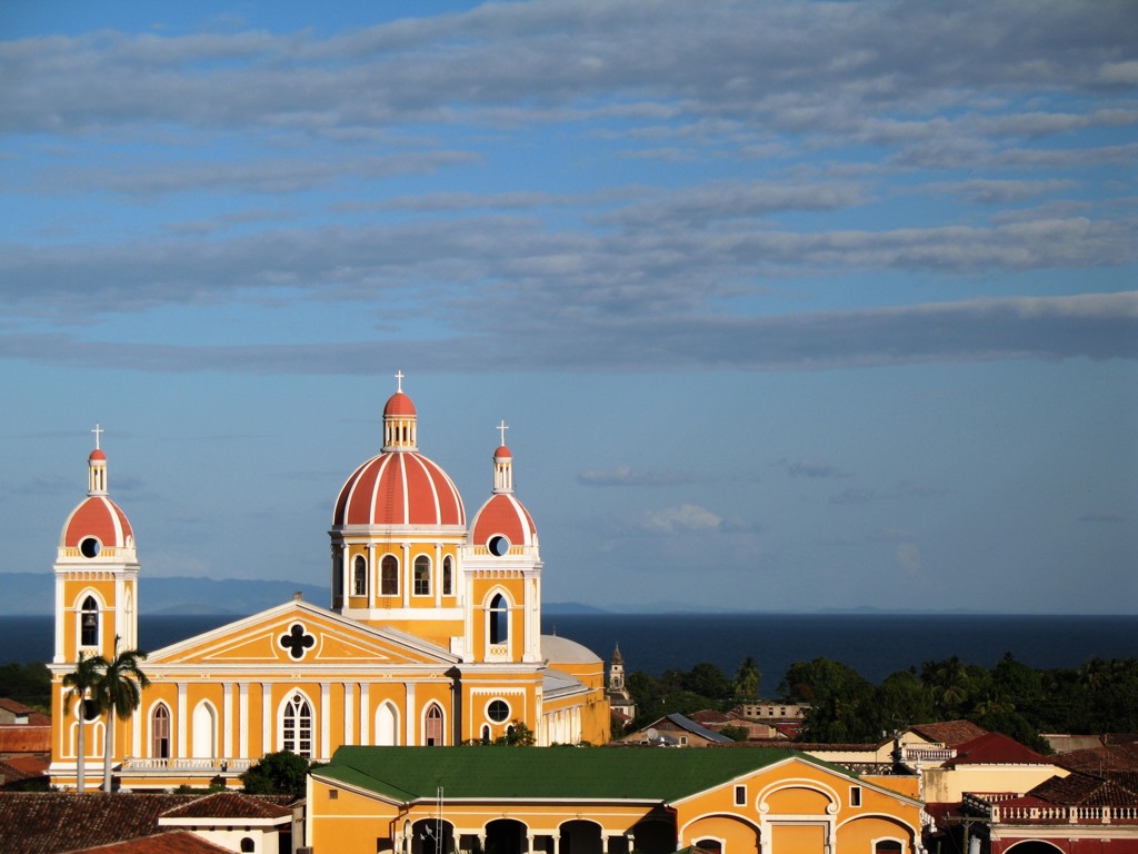 Kathedraal van Granada in Nicaragua met rode koepels en uitzicht op de stad onder een blauwe lucht.
