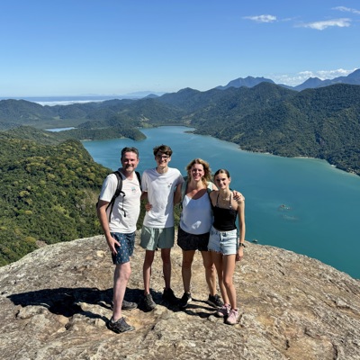 Gezin op een bergtop met uitzicht over een blauw meer en groene bergen tijdens familiereis Argentinië en Brazilië.