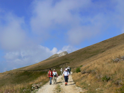 Wandelaars op bergpad door droog grasland tijdens de Route Balkan in Kroatië en Montenegro.