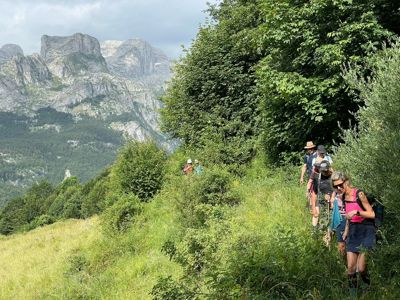 Wandelaars op een groen bergpad met uitzicht op ruige bergtoppen tijdens de Route Balkan wandelrondreis.