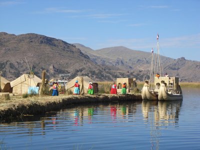 Rieteilanden en totora-rietboten op het Titicacameer in Peru, met bergen op de achtergrond.