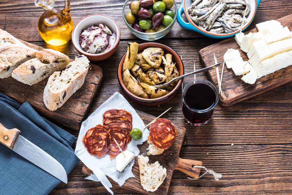 Spaanse tapas met olijven, brood, chorizo, kaas, ansjovis en wijn op houten tafel in Andalusië.