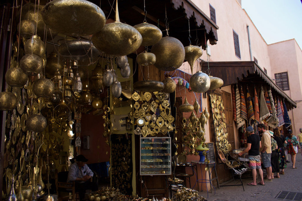 Souk in Marokko met hangende metalen lampen en winkels met handwerk en tapijten.