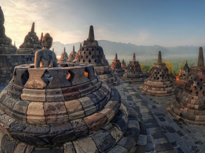 Zonsopgang bij Borobudur met Boeddhabeeld en stoepa’s, Java, Indonesië.